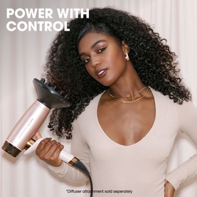 Model with GHD Deluxe Speed Hair Dryer in Cashmere Beige, fitted with diffuser attachment, styling curly hair