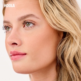Model wearing Benefit Hoola make-up set, showcasing a natural bronzed complexion with defined lashes and a soft pink lip