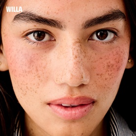 Close-up of model's bare, freckled skin with natural brows, showcasing Benefit Beauty All make-up set finish