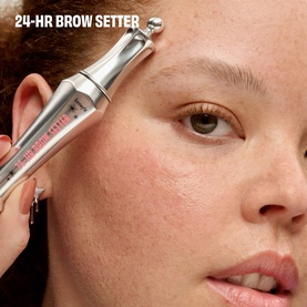 Model with Benefit 24-Hr Brow Setter gel pencil applied to brow, close-up beauty shot showing silver applicator tip