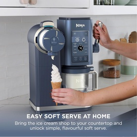 Ninja Swirl by CREAMi 13-in-1 Ice Cream Maker in navy on countertop, dispensing soft serve ice cream into a cone.