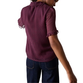 Model wearing Whistles red polka dot short-sleeve blouse with frill collar and cuffs, styled with dark navy jeans, back view.