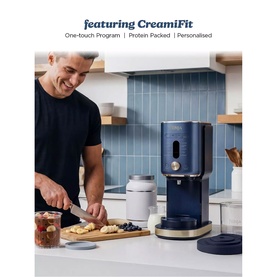 Ninja Ice Cream Maker 11-in-1 in navy blue with gold accents on kitchen counter, man chopping fruit alongside blueberries and toppings
