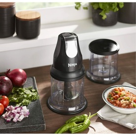 Ninja Stackable Chopper 200W in black, shown with two bowls and fresh vegetables including peppers, onions and tomatoes on a kitchen counter.