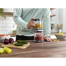 Ninja Stackable Chopper 200W in Black, shown in use on a kitchen counter with fresh vegetables nearby, two stacked chopper bowls filled with