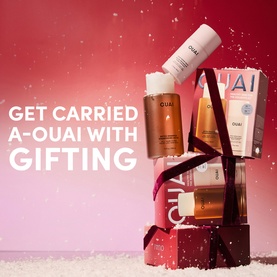 Ouai Hair Care Gift Set arranged on red gift boxes with ribbon, featuring multiple haircare bottles and boxes in festive snowy setting