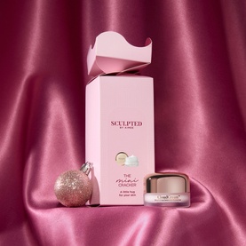 Sculpted by Aimee Mini Boost Make Up Set in pink gift box with cream jar, styled with a pink bauble on pink satin background.