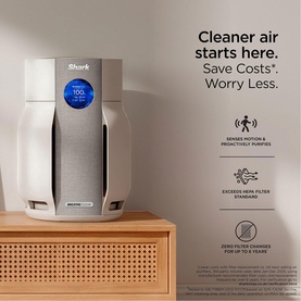 Shark Breathe Clear Compact Dove air purifier in grey-white, displayed on wooden cabinet with feature callouts including HEPA filter standard.