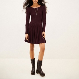 Model wearing Bash purple ribbed knit long-sleeve fit-and-flare mini dress, styled with black leather knee-high boots and a delicate necklace.