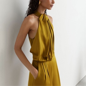 Model wearing Reiss chartreuse green halterneck dress with gathered neckline, sleeveless cut and side pockets, styled with gold earrings