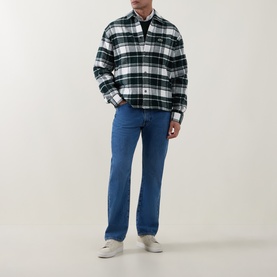 Model wearing Lacoste Casual Shirt in Flour, green and white tartan check, styled with blue straight-leg jeans and white trainers.