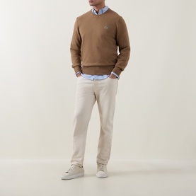 Model wearing Lacoste cookie wool crew neck jumper, styled with a blue shirt, stone chinos and white trainers.