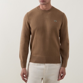 Model wearing Lacoste Cookie wool crew neck jumper with logo badge, styled with white trousers