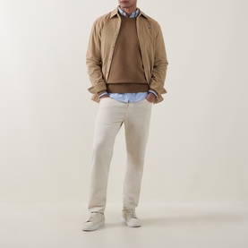 Model wearing Lacoste Cookie wool crew neck jumper, styled with a light blue shirt, beige jacket, cream trousers and white trainers.