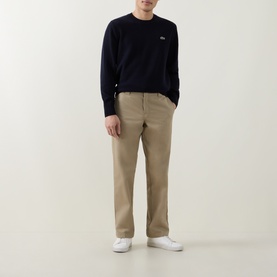 Model wearing Lacoste Navy Blue wool crew neck jumper with small logo detail, styled with beige chinos and white trainers.