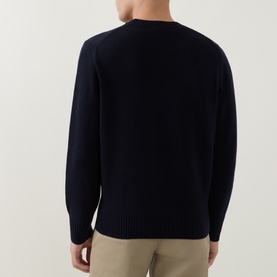 Model wearing Lacoste navy blue wool crew neck jumper, rear view, styled with stone chino trousers