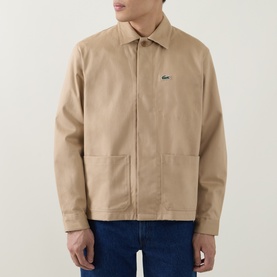 Model wearing Lacoste Overshirt in Viennese beige cotton, zip front, patch pockets, signature crocodile logo, styled with blue jeans.