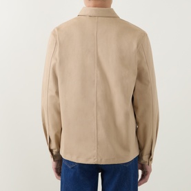Model wearing Lacoste overshirt in Viennese beige cotton, rear view, styled with blue denim jeans