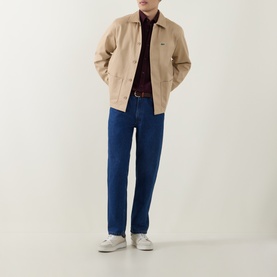 Model wearing Lacoste Viennese cotton overshirt with burgundy polo, blue jeans and white trainers.