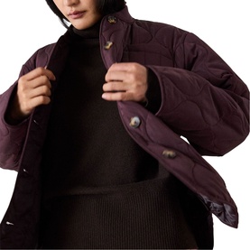 Model wearing Whistles red quilted jacket with snap button fastening, styled with black roll-neck top and knit skirt