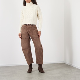 Model wearing Nili Lotan ivory lambswool cable-knit turtleneck sweater, styled with brown wide-leg trousers and ankle boots.