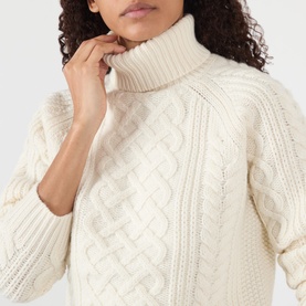 Model wearing Nili Lotan ivory lambswool cable-knit turtleneck sweater with balloon sleeves, close-up detail shot.