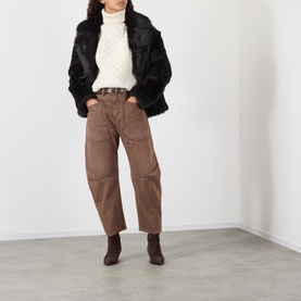 Model wearing Nili Lotan ivory lambswool cable-knit turtleneck, styled with black faux fur jacket, brown cargo trousers and ankle boots.