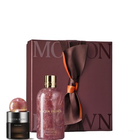 Molton Brown fragrance gift set with large pink marbled bath bottle, small black fragrance jar, and burgundy ribbon-tied gift box.