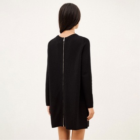 Model wearing Bash black mini dress with long sleeves, shown from behind with visible gold zip detail down the back.