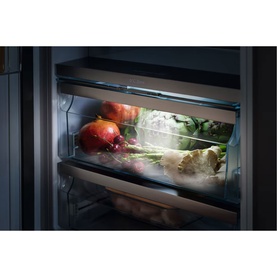 Miele Built-in 70/30 Fridge-Freezer interior showing illuminated PerfectFresh Active drawer with fresh vegetables and fruit