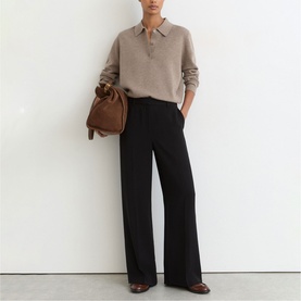 Model wearing Reiss beige knit polo top with black wide-leg trousers, styled with brown leather bucket bag and dark heels.
