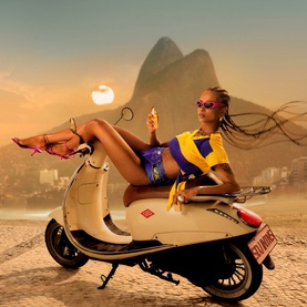 Sol De Janeiro Cheirosa 62 Intense Perfume Mist lifestyle shot featuring model reclining on a scooter against a Rio de Janeiro beach backdrop.