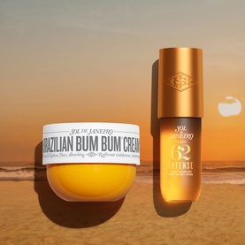 Sol De Janeiro Cheirosa 62 Intense Perfume Mist in amber bottle beside Brazilian Bum Bum Cream jar, beach sunset backdrop
