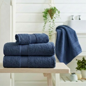 Deyongs Indigo plain towel set displayed on wooden shelf in bathroom setting, showing bath sheet, bath towel and hand towel