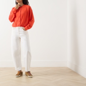 Model wearing American Vintage coral knit top with white wide-leg jeans and tan lace-up shoes
