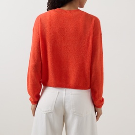 Model wearing American Vintage coral knit jumper, back view, styled with white wide-leg jeans