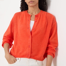 Model wearing American Vintage coral knit cardigan with round neck and button-front fastening, styled with a white top