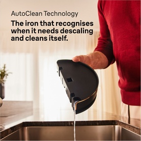 Braun CareStyle 9 Steam Generator Iron in black, tilted over a sink demonstrating AutoClean self-descaling technology with water draining out.