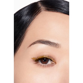 Close-up of model's eye wearing Chanel eye liner in golden yellow shade with defined lashes and natural brow