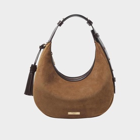 Tan suede crescent hobo bag with gold-tone logo plate, dark brown leather trim, tassel detail, and top handle