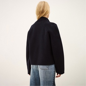 Model wearing Bash blue short wool jacket, back view, styled with light wash wide-leg jeans