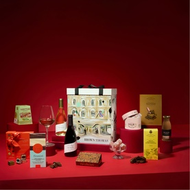 Brown Thomas Food Retail Hamper with branded tote bag, wine, chocolates, biscuits, preserves and festive treats on red background
