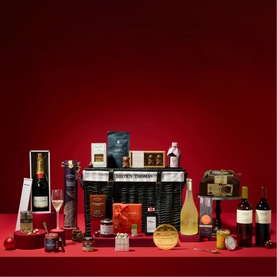 Brown Thomas multi food hamper filled with wines, champagne, snacks and festive treats, displayed on red background
