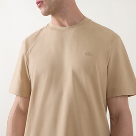 Model wearing Lacoste Crew Neck T in beige cotton, featuring a small tonal crocodile logo on the chest.