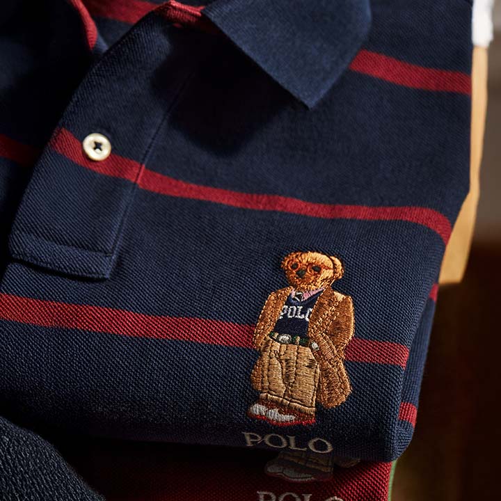 Navy blue polo shirt with red stripes and an embroidered teddy bear wearing a Polo outfit.
