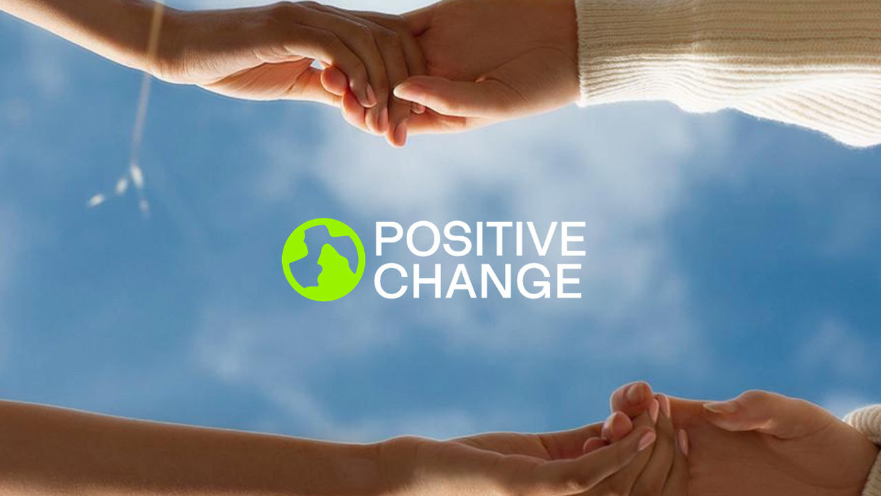 Two pairs of hands clasped against a blue sky backdrop, with 'Positive Change' written in the center.
