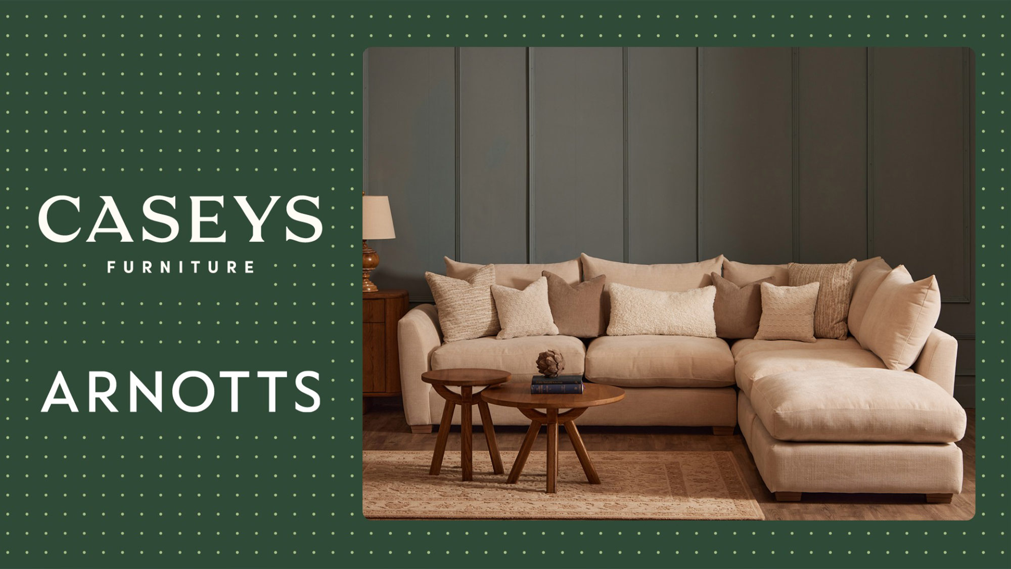 A cozy living room setup featuring a beige sectional sofa, matching ottoman, and wooden side tables, against a paneled wall.

