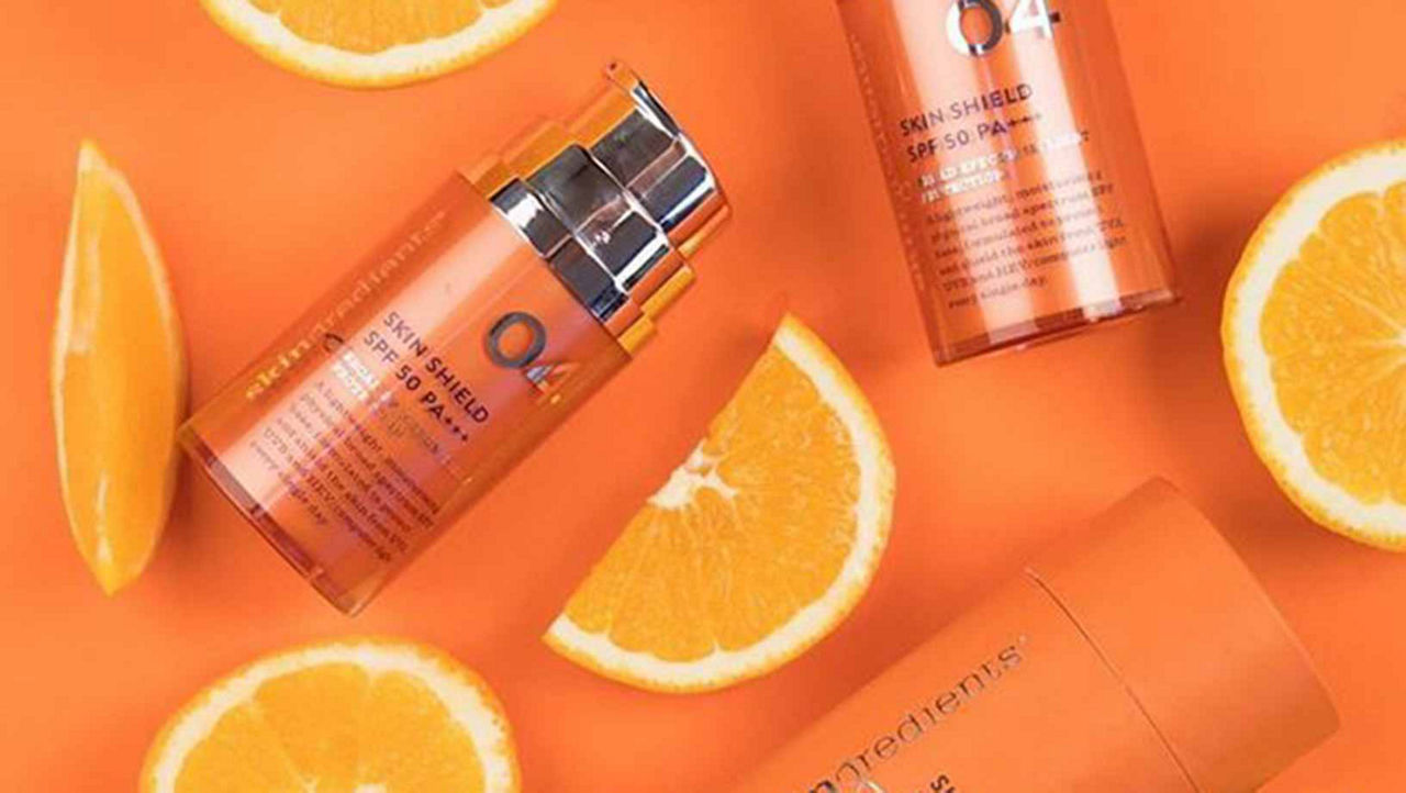 Skingredient Skin Shield SPF 50+++ on an orange background surrounded with orange segments