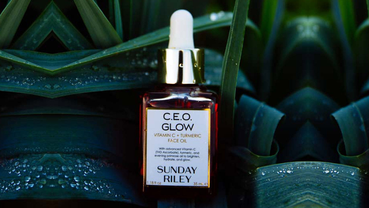 A bottle of Sunday Riley C.E.O. Glow face oil is surrounded by lush greenery, emphasizing a 'sustainable edit' context.