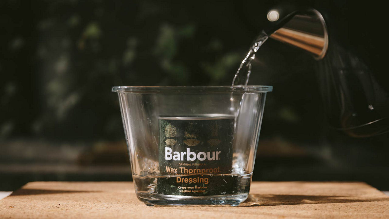 Pot of Barbour jacket wax in foreground in pot of boiling water